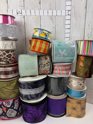 Assorted rolls of ribbon on a wooden surface with a ruler.