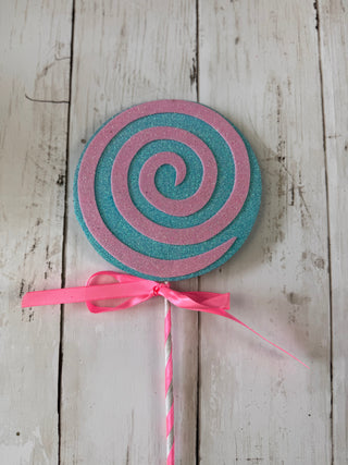 Pink and blue spiral lollipop-shaped object on a wooden surface