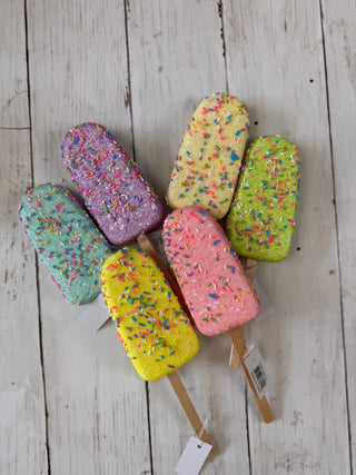 Colorful ice cream popsicles with sprinkles on a wooden surface